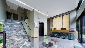 A modern lobby with a marble staircase, a reception desk, and a seating area with two tables. - PIN Hotel Guangzhou Beijing Road Pedestrian Street Gongyuanqian Metro Station Branch - Free Deliver Service to Guangzhou Baiyun International Airport & Free Deliver Service to Canton Fair Complex During Canton Fair Period (Guangzhou)