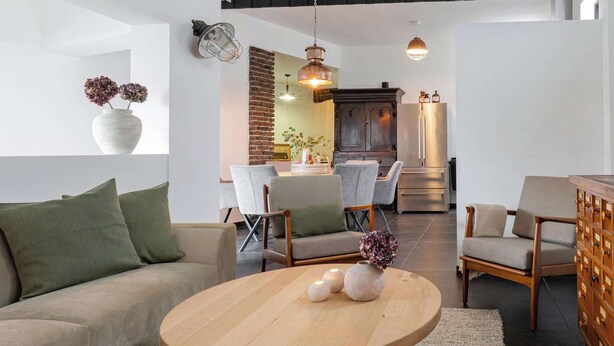 Ein geräumiger Loft mit hoher Decke, freiliegenden Balken, einem Essbereich mit einer Ziegelwand als Blickfang und einer modernen Küche mit Edelstahlgeräten.
