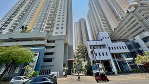 De grands immeubles résidentiels dotés de balcons, une rue avec des véhicules et un ciel dégagé.