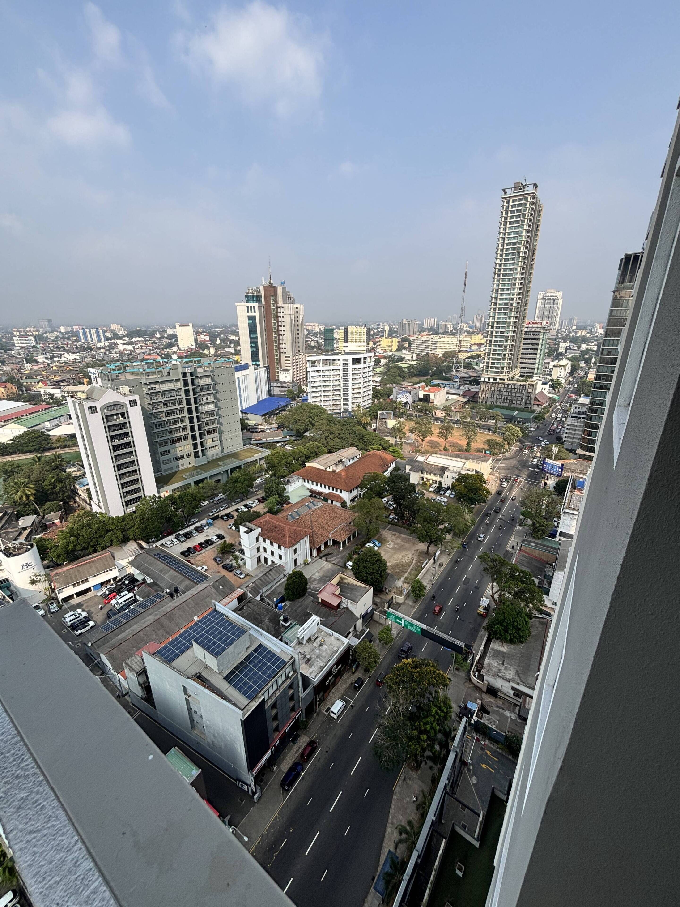 A cityscape with high-rise buildings, a clear sky, and a road with vehicles.