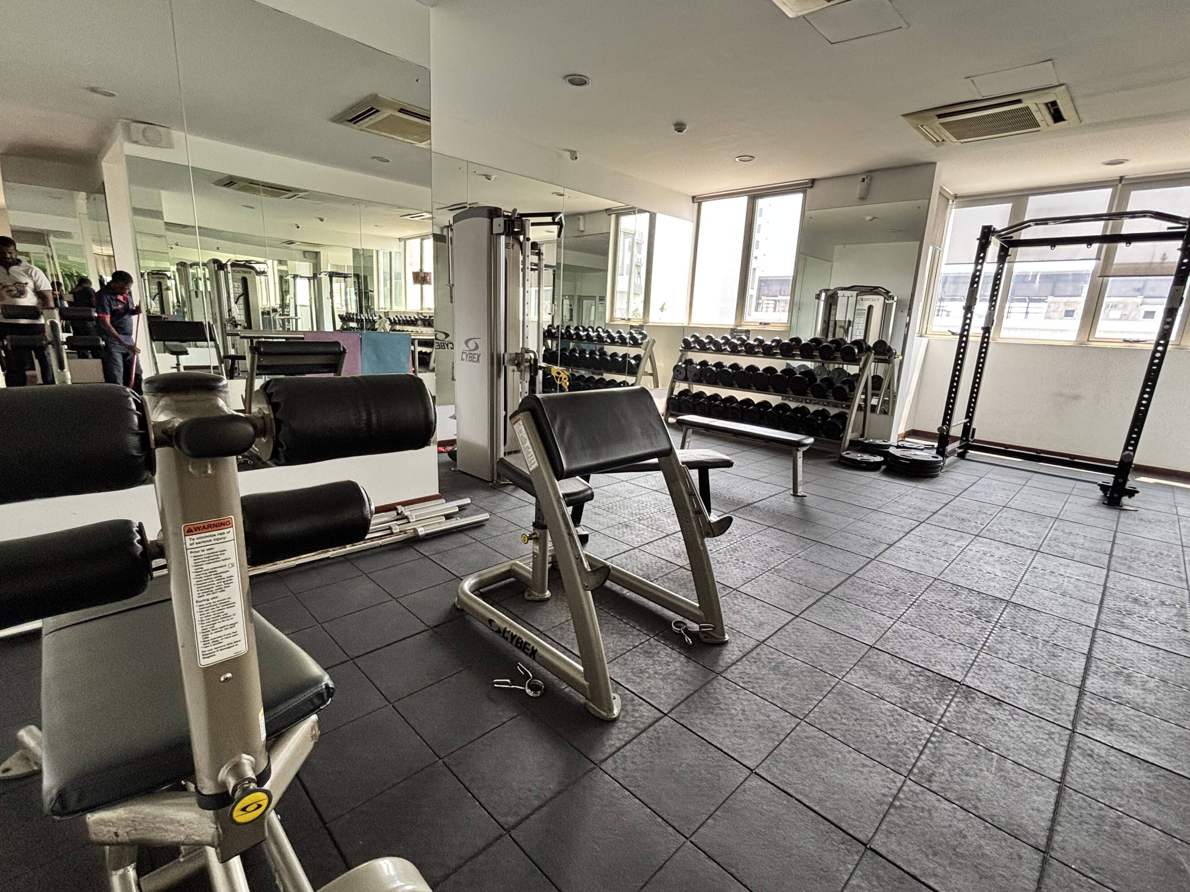 A gym with exercise equipment, weights, and a mirror.