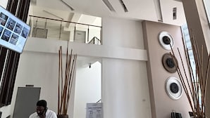Un hall d’entrée moderne doté d’un comptoir de réception, d’un écran numérique et d’un escalier menant à un étage supérieur.