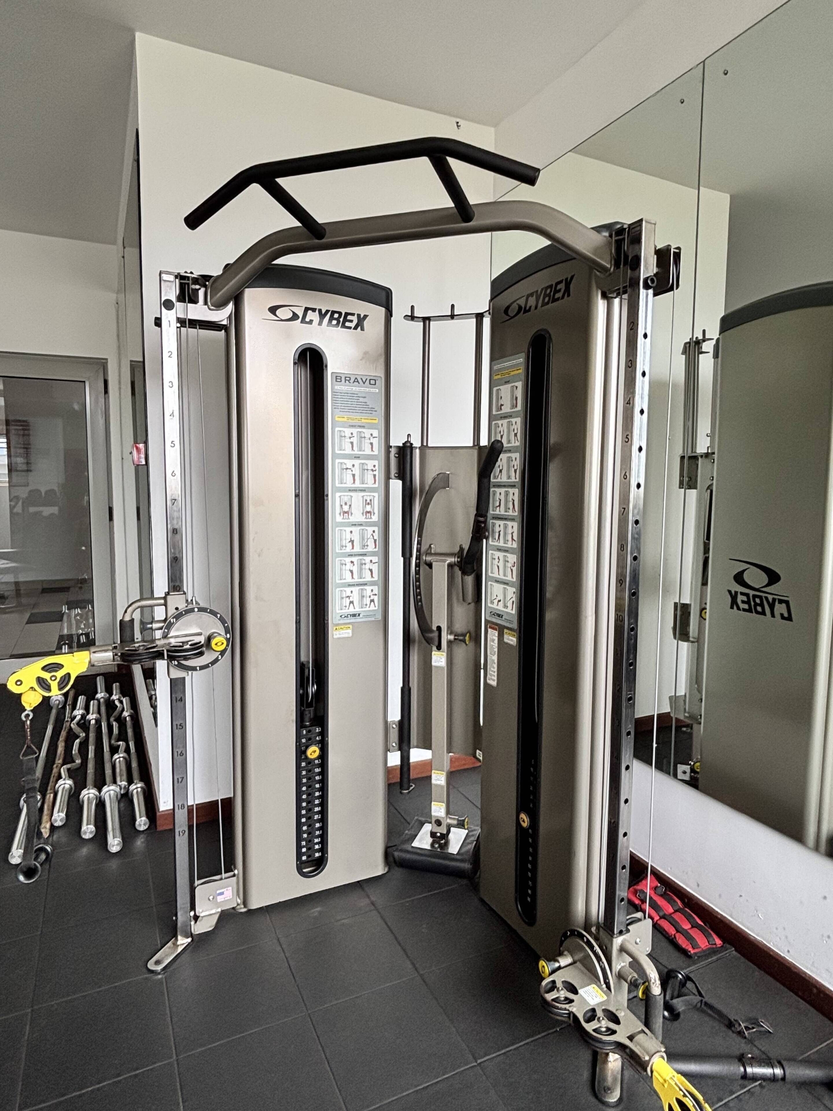 A gym with Cybex equipment, a mirror, and a door.