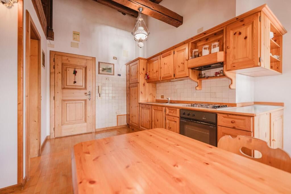 A kitchen with wooden cabinets, a wooden table, and a hanging light fixture.