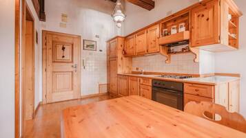 A kitchen with wooden cabinets, a wooden table, and a hanging light fixture.