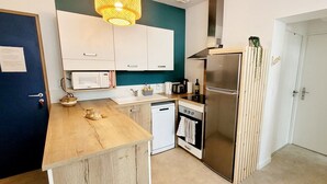 A compact kitchen with white cabinets, a stainless steel refrigerator, a microwave, and a small oven. - Forest Apartment – Shared Pool (La Tranche-sur-Mer)