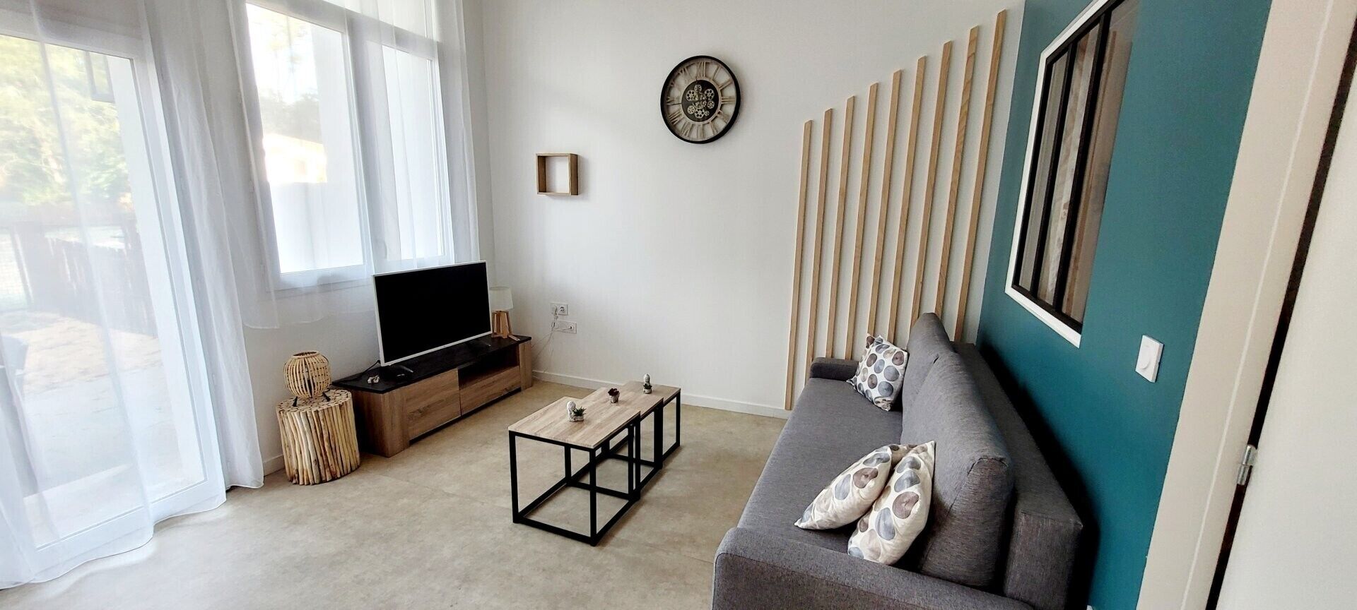 Un salon comprenant un canapé, un téléviseur, une table basse et une horloge murale.