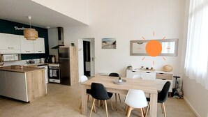 A modern kitchen with a wooden island, white cabinets, and a hanging light fixture. - Forest Apartment – Shared Pool (La Tranche-sur-Mer)