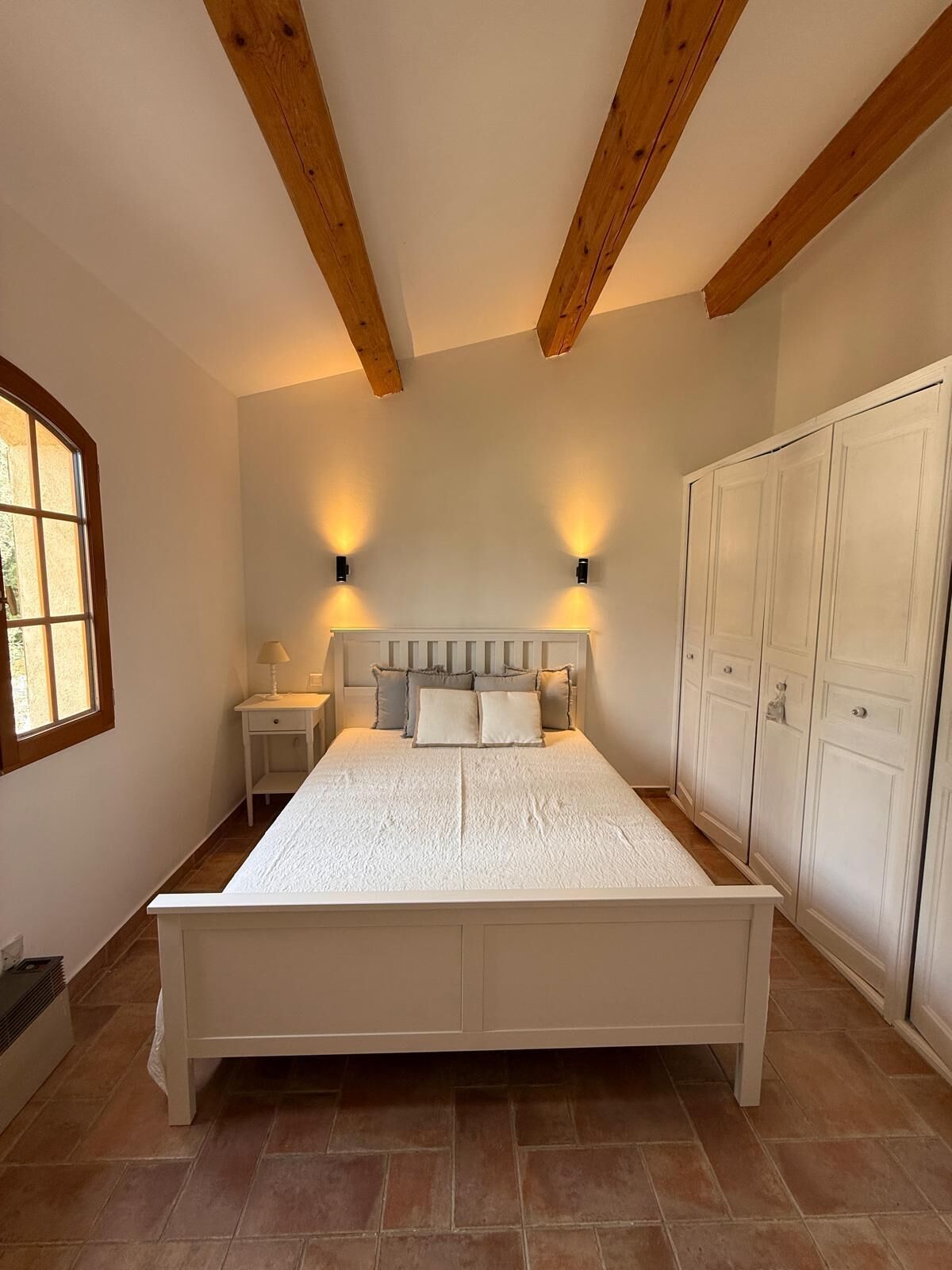 Een slaapkamer met een bed, nachtkastjes, een kledingkast en een raam.