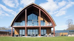 A modern building with a large balcony, large windows, and a wooden facade. - Private Wellness Haven by the Vecht (Dalfsen)