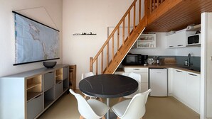 Una cocina compacta con comedor, una escalera de madera y un mapa en la pared.