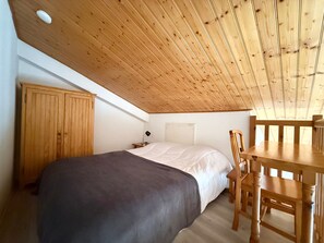 A bedroom with a wooden ceiling, a bed, a nightstand, a desk, and a chair. - Cozy house, pets allowed - 4 guests (Barbâtre)