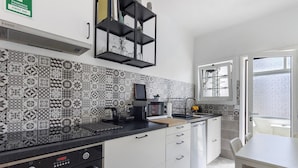 Une cuisine avec des carreaux décoratifs, un four à micro-ondes, un grille-pain et un évier.