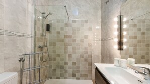 Une salle de bain moderne avec une douche à parois de verre, un lavabo blanc et un miroir avec éclairage intégré.