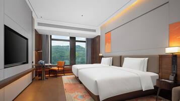 A hotel room with a large bed, a desk with a chair, a television, and a view of the outdoors.