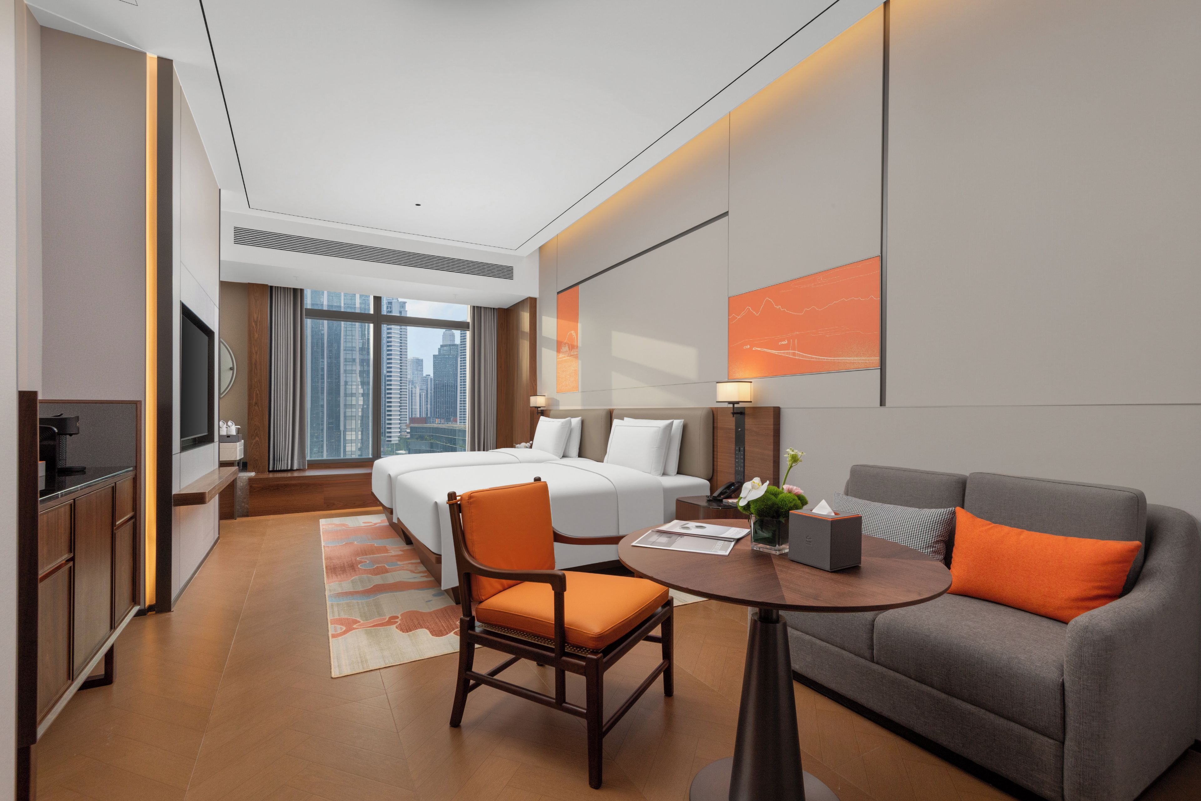 Ein Hotelzimmer mit Bett, einer Couch, einem Sessel, einem Schreibtisch und Blick auf die Stadt.