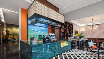 A modern bar area with a marble countertop, shelves with bottles, and a cityscape mural.