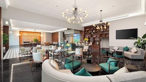 Un vestíbulo amplio con una zona de bar, asientos y un moderno candelabro.