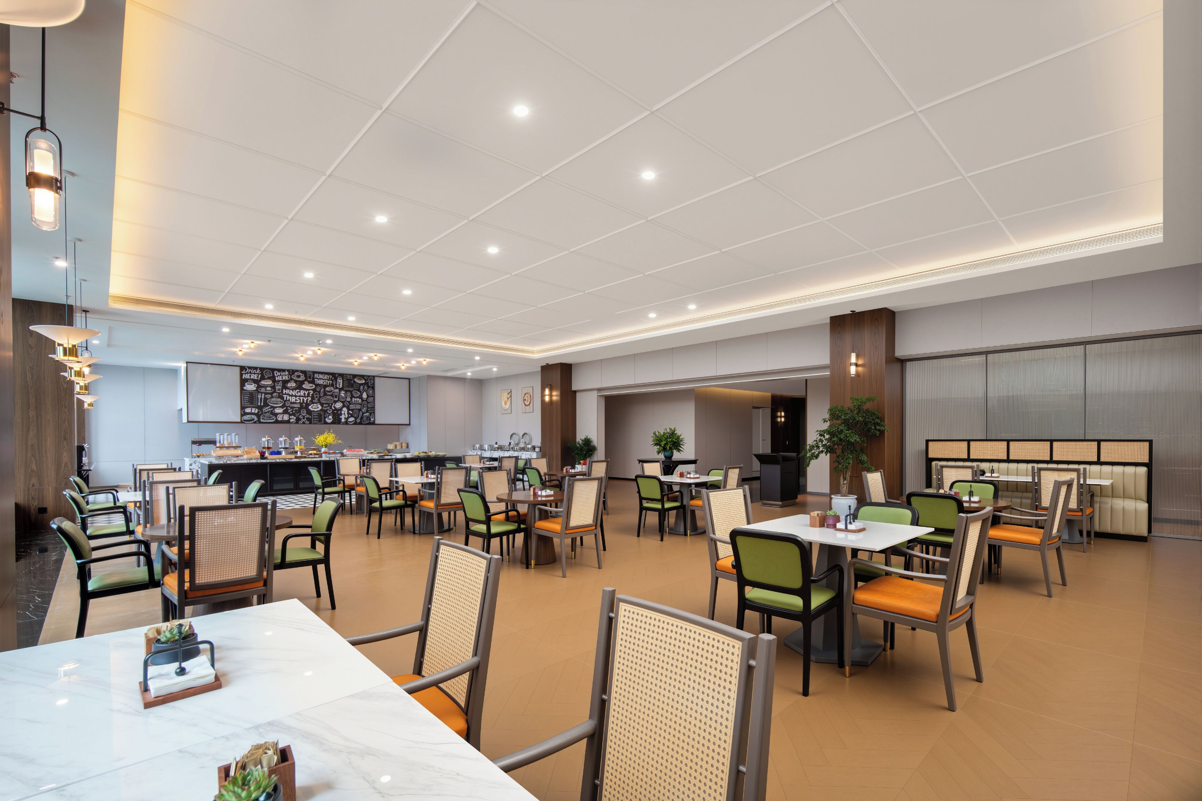 A spacious dining area with multiple tables and chairs, a central serving station, and a modern ceiling design.