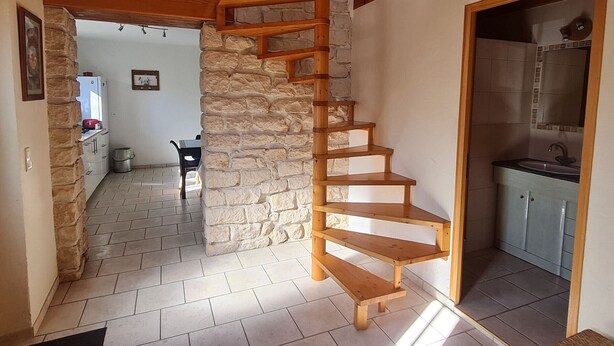 Una scala a chiocciola in un ambiente rustico con pareti in pietra e travi in legno.