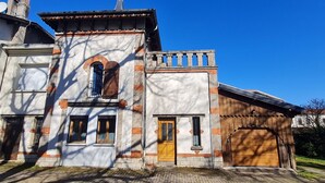Un edificio a due piani con facciata in mattoni, un'ampia finestra ad arco e un portone garage.