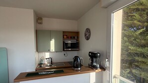 Une petite cuisine équipée d’un four à micro-ondes, d’une machine à café et d’une horloge murale.