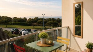 Un balcon avec une table, des chaises et une vue sur la mer.