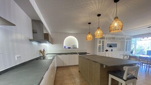 A modern kitchen with white cabinets, a central island, and pendant lighting. - Seafront apartment with views - NOR guests (La Mora)