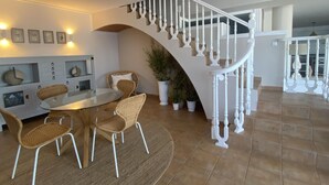 A modern interior with a dining area, white staircase, and potted plants. - Seafront apartment with views - NOR guests (La Mora)