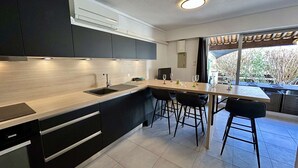 Una cocina moderna con una isla central, taburetes de bar y vistas al exterior.