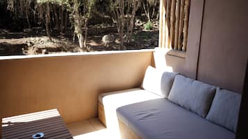 Un balcon doté d’un espace salon avec des coussins, d’une petite table et offrant une vue sur un paysage naturel.