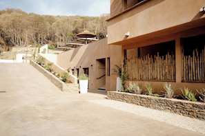 A modern building with a stone pathway, a wooden fence, and a staircase leading to the entrance.