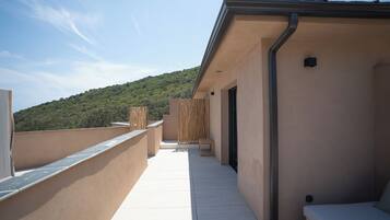 Una terraza en la azotea con vistas a una colina verde, una valla de madera y un pequeño espacio para sentarse.