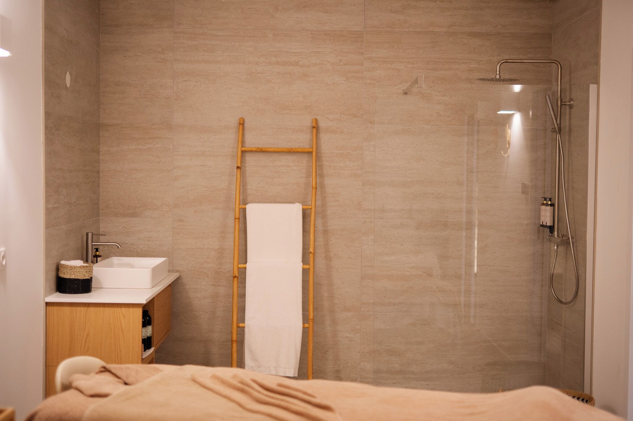 Un baño moderno con ducha, una escalera de madera, un lavamanos y un perchero para toallas.