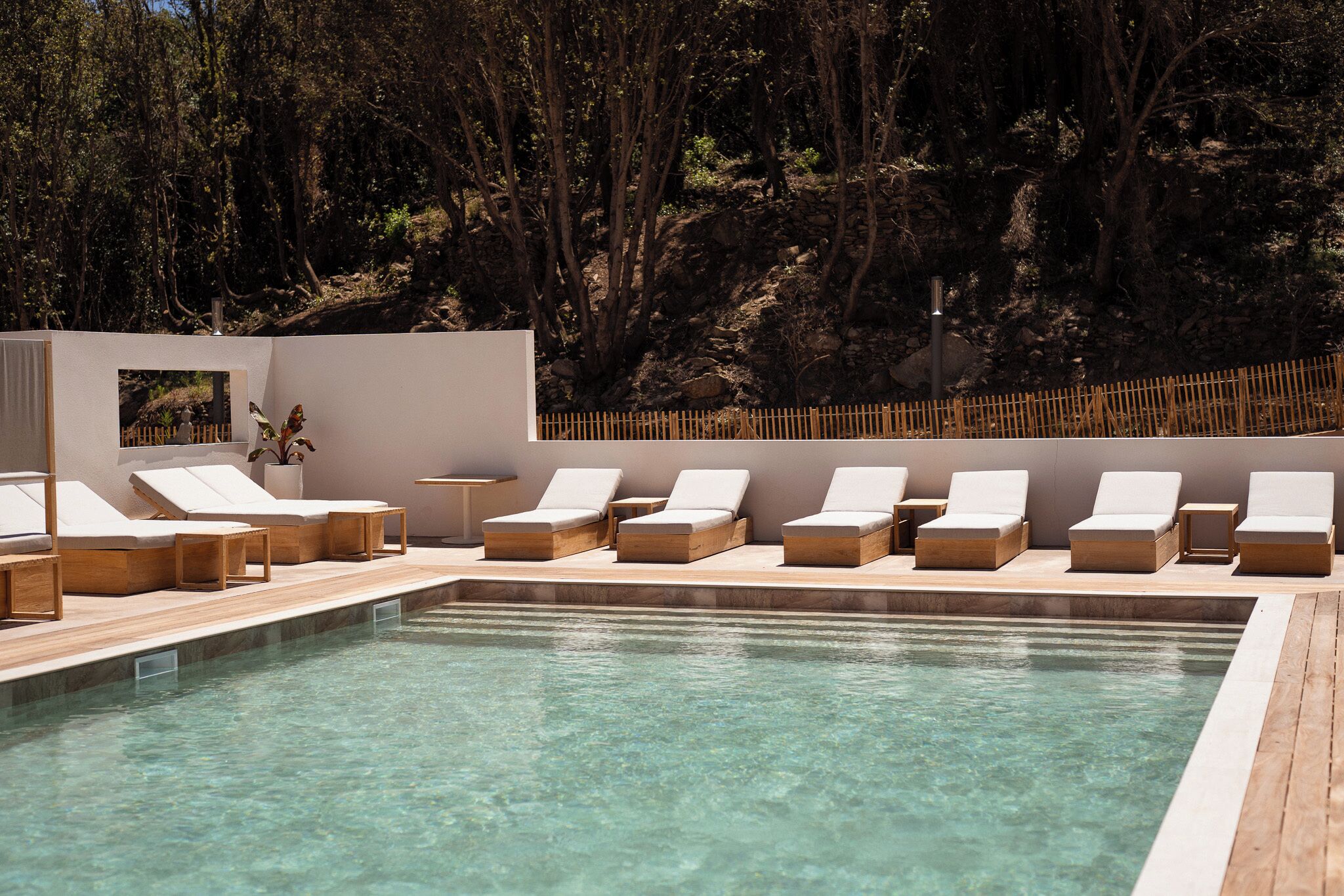 Ein Pool mit klarem Wasser, umgeben von Holzliegen und einer Holzterrasse.