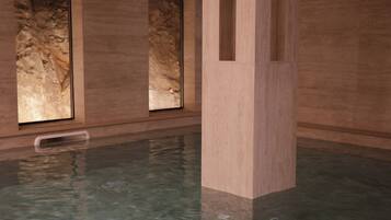 A swimming pool with clear water, surrounded by stone walls and large windows.