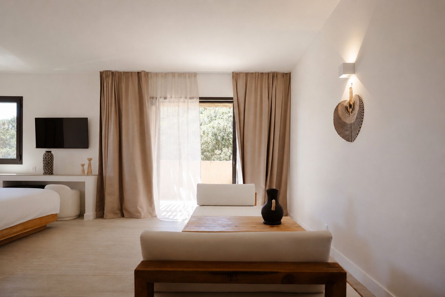 Quarto com cama, mesa de cabeceira, luminária, cortinas e uma televisão.
