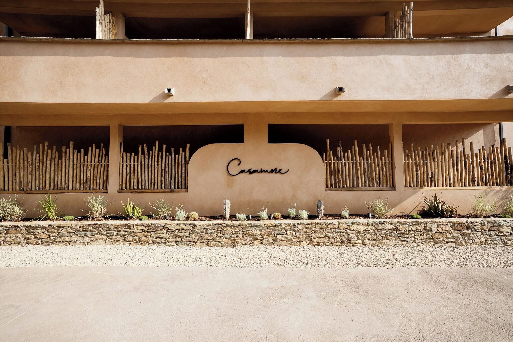 A building facade with a sign reading 'Casanova,' a stone wall, and a row of cacti.