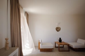 Ein schlicht eingerichteter Raum mit einer Couch, einem kleinen Tisch und einer Wanddekoration.