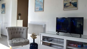 A living room with a television, a chair, a vase with dried flowers, and framed posters on the wall. - House near the sea - 5 guests (Noirmoutier-en-l'Île)
