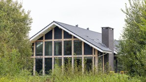 Ett modernt hus med ett sluttande tak, stora fönster och en skorsten.