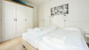 A bedroom with a bed, two white nightstands, a large wardrobe, and a wall-mounted artwork. - Modern Coast Villa With Private Patio (Egmond aan Zee)
