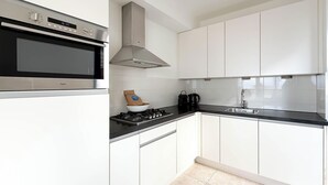 A modern kitchen with white cabinets, a stainless steel oven, a gas stove, and a sink. - Modern Coast Villa With Private Patio (Egmond aan Zee)