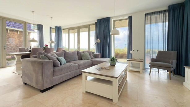 A spacious living room with a large sofa, a coffee table, and a dining area with a table and chairs. - Modern Coast Villa With Private Patio (Egmond aan Zee)
