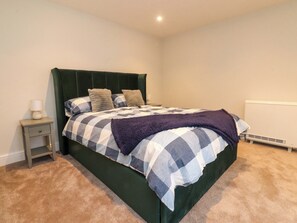 A bedroom with a bed, a bedside table, and a radiator. - Cowside Farm (Settle)
