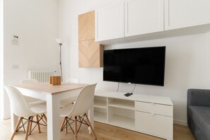 A modern living space with a dining table, chairs, a TV mounted on the wall, and a sofa. - Cozy 53m2 apartment, perfect for 3 people, located on the raised ground floor.The accommodation is located in the Barona area, close to the Naviglio Grande and characterized by a rural soul with ancient farmhouses and recent urban redevelopment.The area  (Milan)