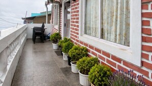 Ein Balkon mit Blumentöpfen, einem Tisch und Stühlen.