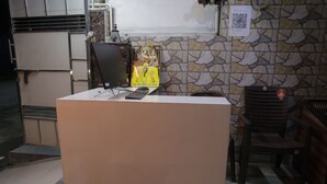 Una recepció amb un ordinador, una cadira i un cartell a la paret.