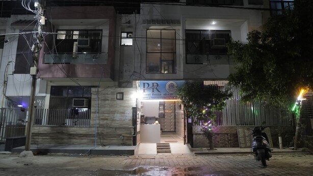 Un edifici amb un rètol que diu 'PR Guest House' i una moto aparcada a l'exterior.