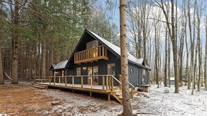 Une cabane dotée d’un balcon, entourée d’arbres et de neige.
